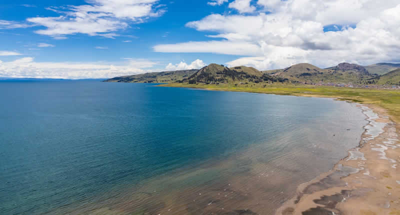 Playa ecoturística de arena fina con paisaje de waru-waru